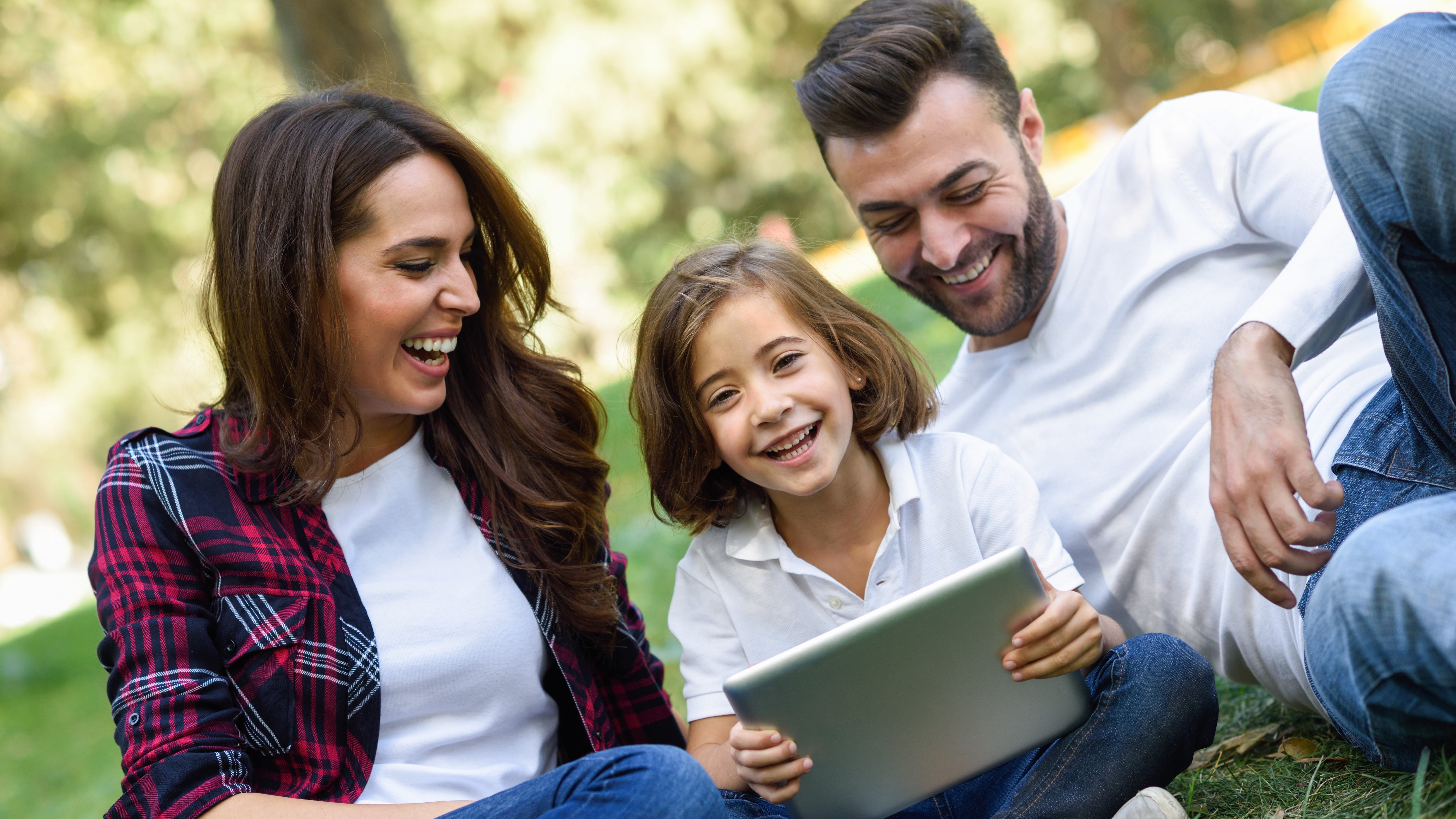 Happy family in a urban park playing with tablet computer